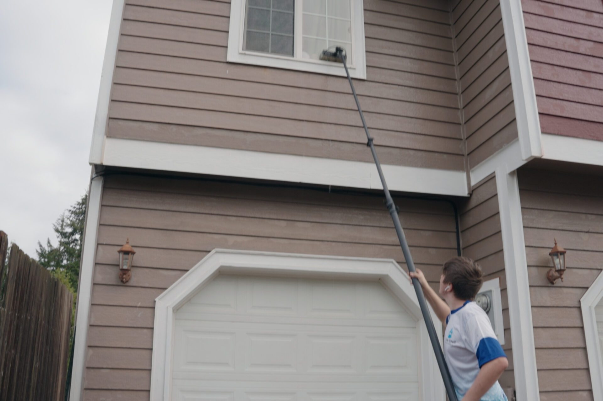 A man diligently cleans a window using a brush, ensuring a clear and spotless surface