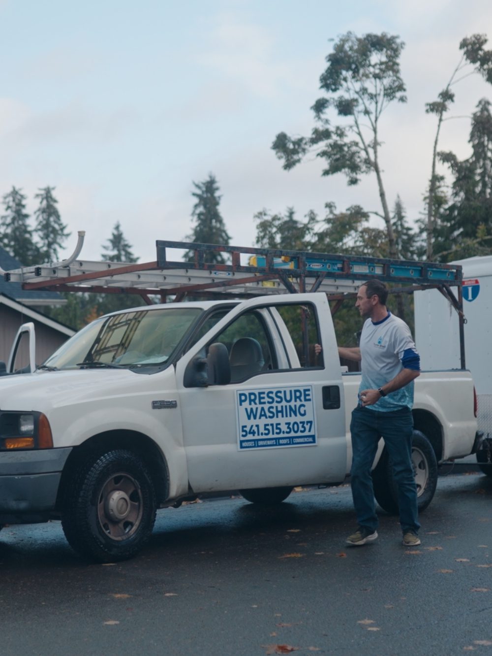 A man stands beside a white truck, showcasing a casual outdoor setting