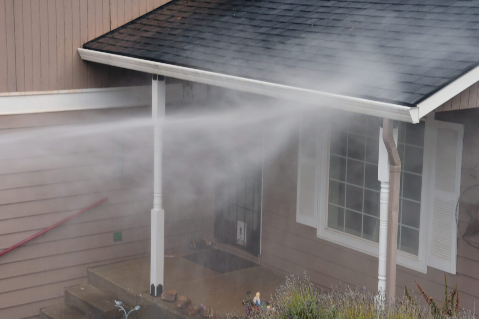 A man sprays water on a house, ensuring its exterior remains clean and well-maintained